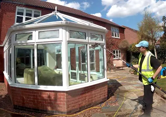 man cleaning exterior windows of conservatory